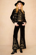 Model wearing a black velvet 70s style suit set with gold embroidery from The Hippie Shake
