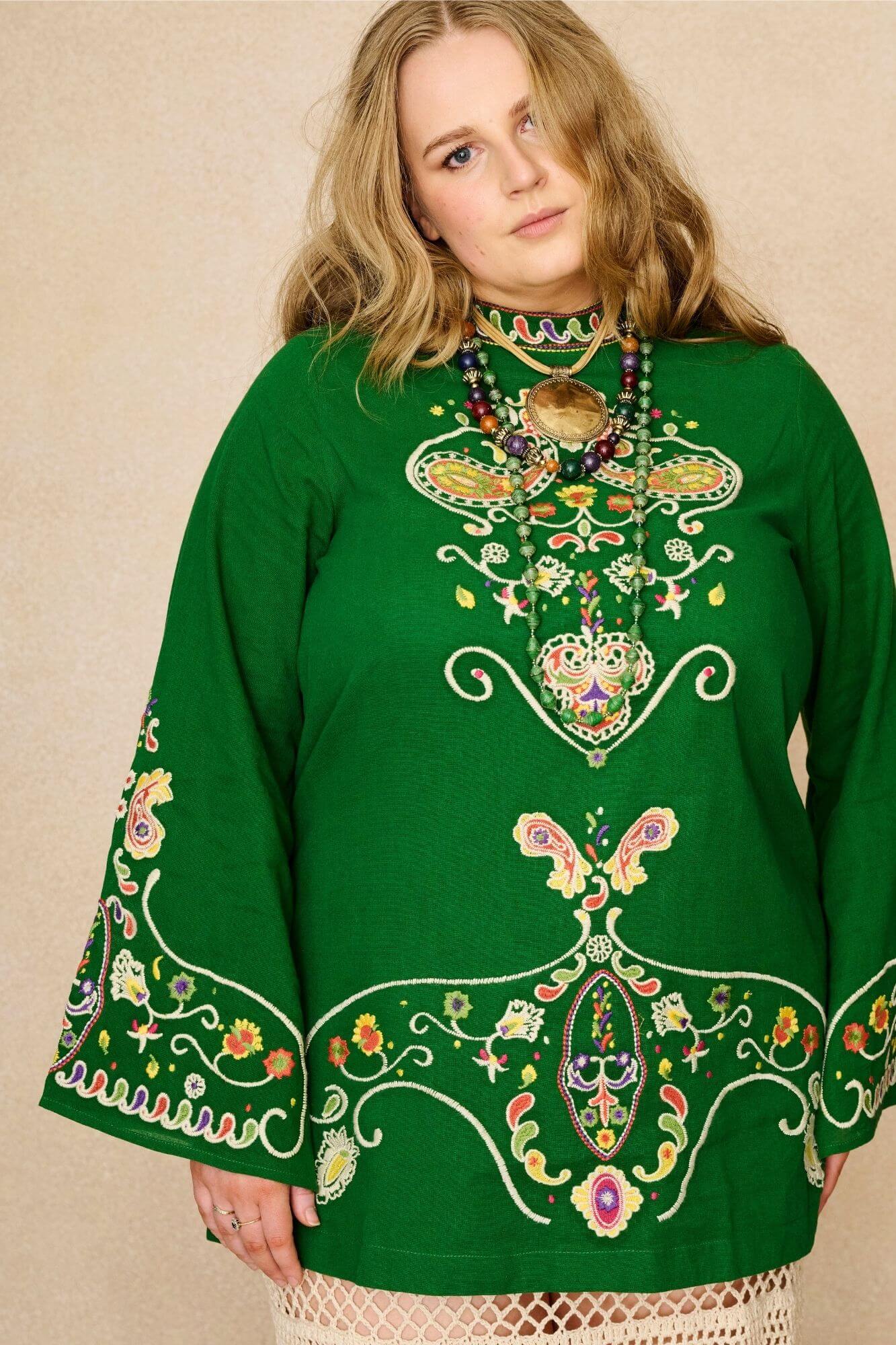Model wearing green folk embroidered mini dress in soft cotton with wide sleeves. A 70s-inspired boho mini dress made for festival and vintage styling by The Hippie Shake