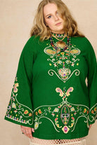 Model wearing green folk embroidered mini dress in soft cotton with wide sleeves. A 70s-inspired boho mini dress made for festival and vintage styling by The Hippie Shake