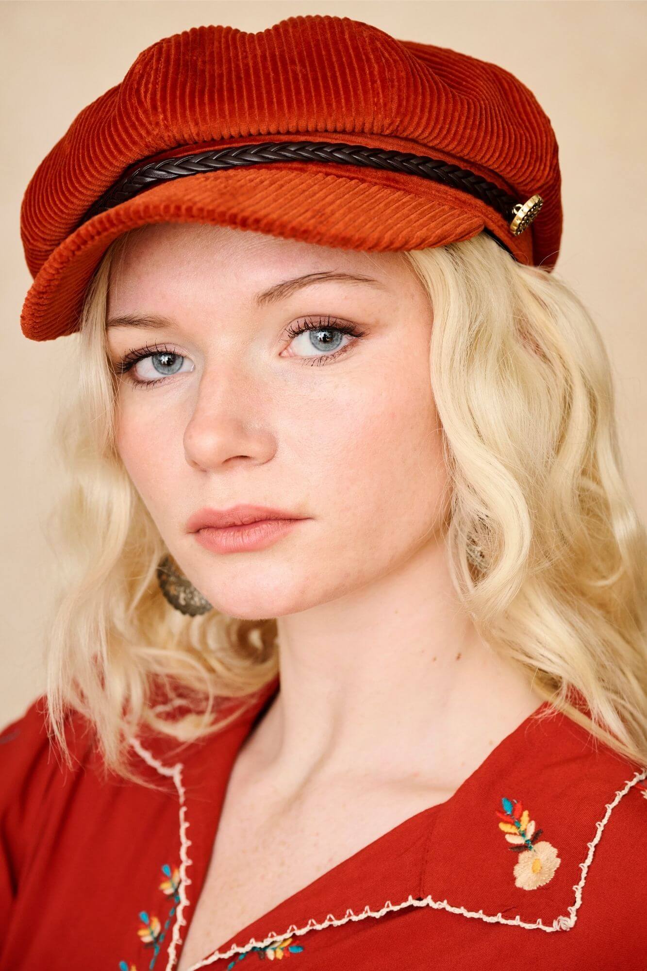 Model wears burnt orange corduroy baker hat with braided trim and vintage detailing. A 70s-inspired boho hat by The Hippie Shake. Front view