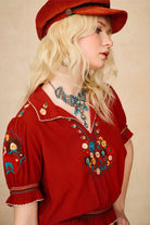 Model wears red floral embroidered Penny Lane blouse in soft cotton with shirred details. A vintage-inspired boho blouse made for everyday and festival styling by The Hippie Shake. Side view