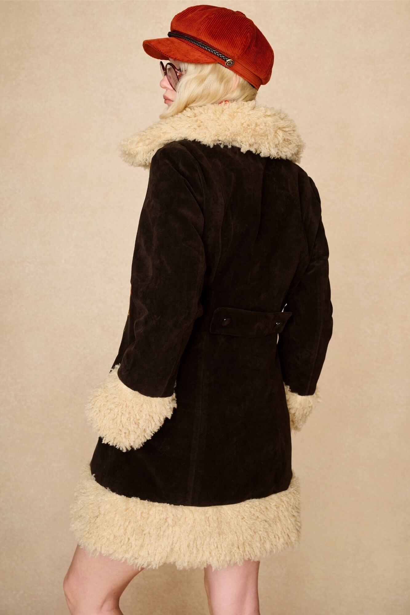 Model wears dark brown embroidered Penny Lane coat in faux suede with faux fur trim. A 70s-inspired statement coat made for bold, vintage boho styling by The Hippie Shake - back view