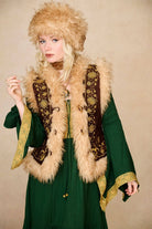 Model wears brown embroidered Penny Lane vest in faux suede with faux fur trim. A 70s-inspired boho layering piece made for vintage and festival styling by The Hippie Shake - front view paired with green dress