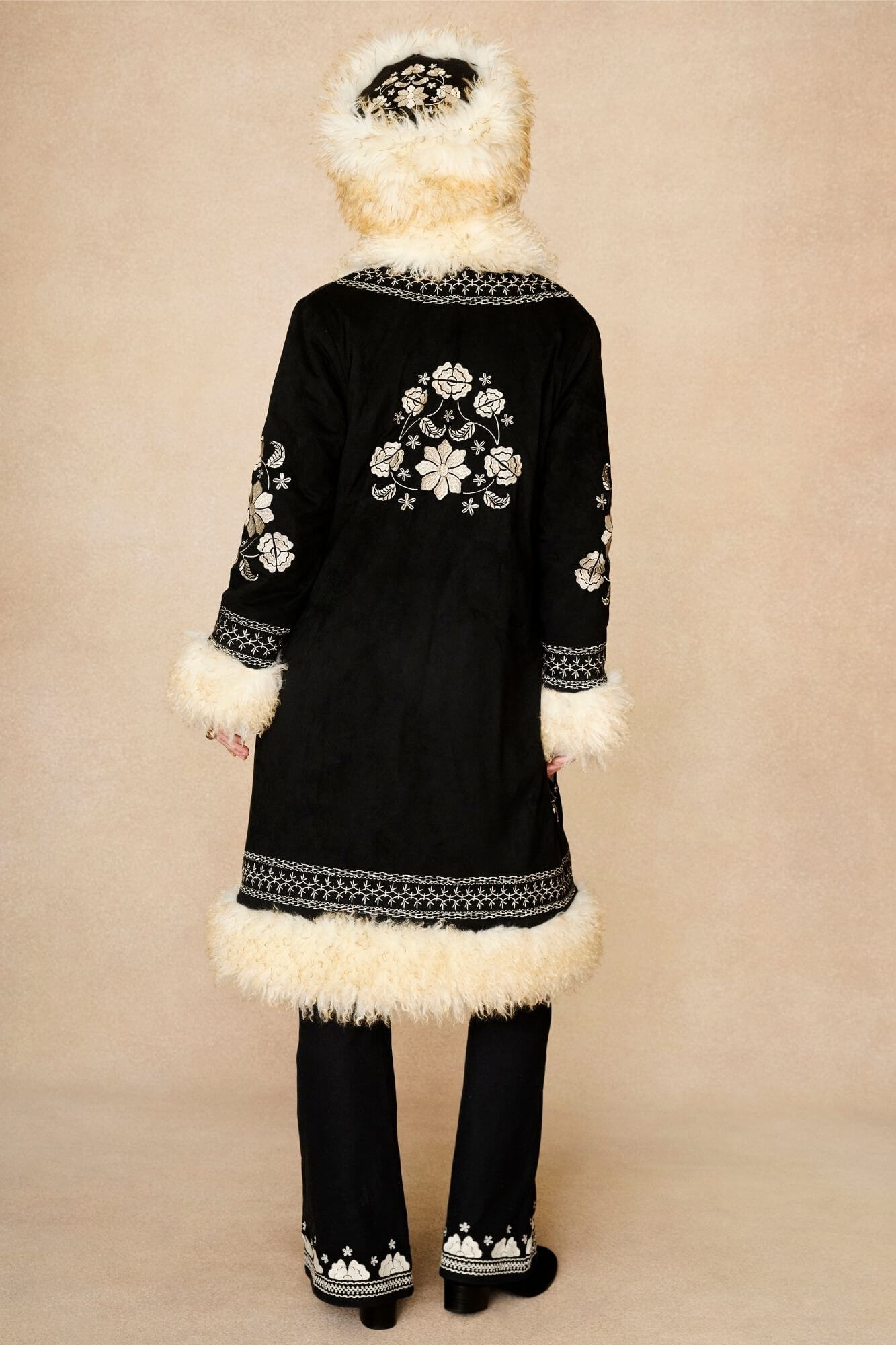 Model wears cream faux fur hat with vintage detailing and embroidered finish. A 70s-inspired boho winter hat made for statement styling by The Hippie Shake - back view with Black Penny Lane coat