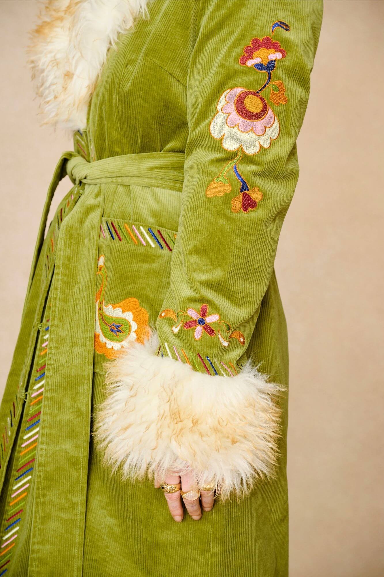 Model wears green embroidered Penny Lane coat in cotton corduroy with faux fur trim. A 70s-inspired statement coat made for bohemian, vintage styling by The Hippie Shake - sleeve detail