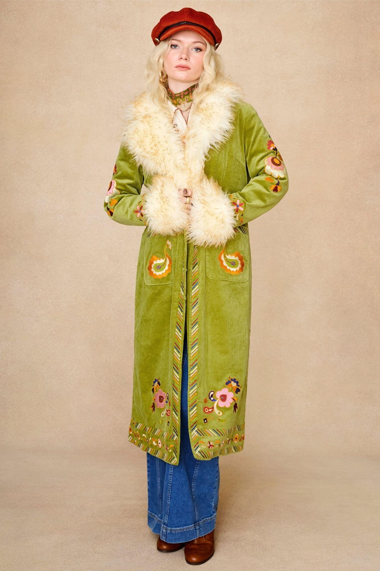 Model wears green embroidered Penny Lane coat in cotton corduroy with faux fur trim. A 70s-inspired statement coat made for bohemian, vintage styling by The Hippie Shake - standing front view