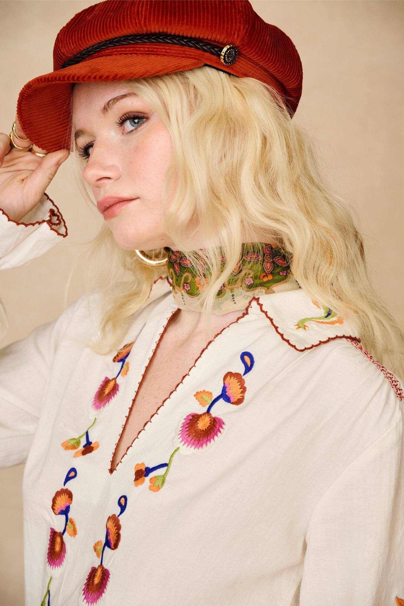 Model wears cream embroidered blouse in textured cotton with floral detailing and balloon sleeves. A 70s-inspired boho blouse made for everyday vintage styling by The Hippie Shake - side view close up