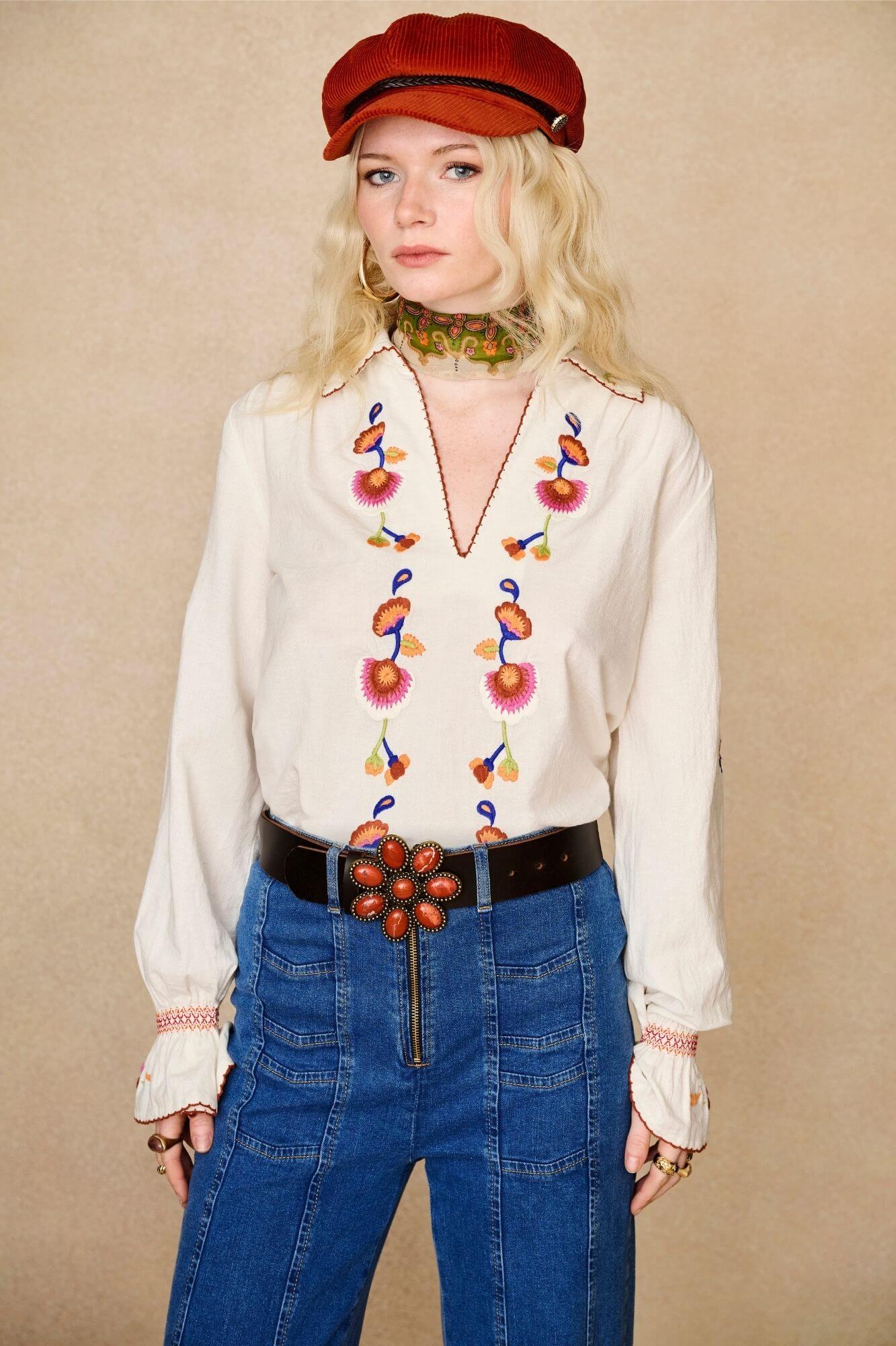 Model wears cream embroidered blouse in textured cotton with floral detailing and balloon sleeves paired with flared denim jeans. A 70s-inspired boho blouse made for everyday vintage styling by The Hippie Shake - front view