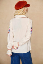 Model wears cream embroidered blouse in textured cotton with floral detailing and balloon sleeves paired with flared denim jeans. A 70s-inspired boho blouse made for everyday vintage styling by The Hippie Shake - back view
