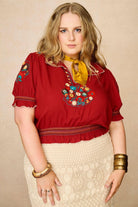 Model wears red floral embroidered Penny Lane blouse in soft cotton with shirred details. A vintage-inspired boho blouse made for everyday and festival styling by The Hippie Shake. Front view