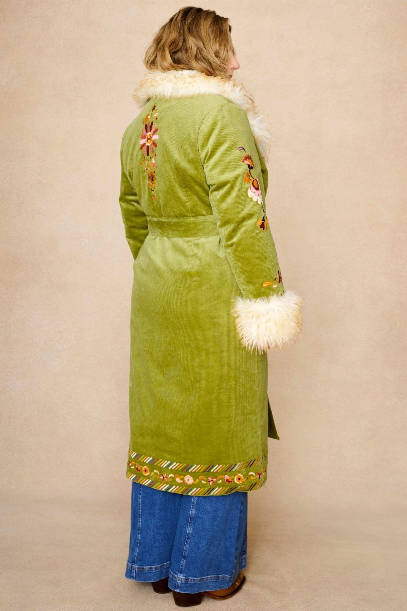 Model wears green embroidered Penny Lane coat in cotton corduroy with faux fur trim. A 70s-inspired statement coat made for bohemian, vintage styling by The Hippie Shake - back view