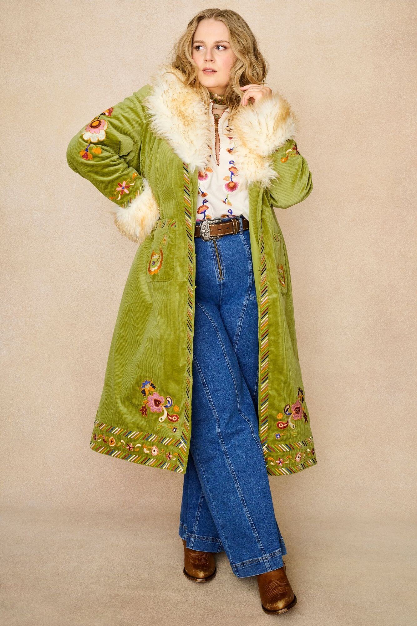 Model wears green embroidered Penny Lane coat in cotton corduroy with faux fur trim. A 70s-inspired statement coat made for bohemian, vintage styling by The Hippie Shake - open front view