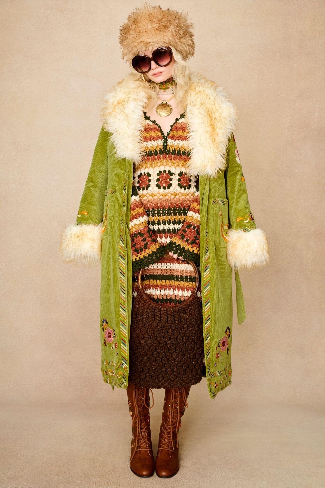 Model wears green embroidered Penny Lane coat in cotton corduroy with faux fur trim. A 70s-inspired statement coat made for bohemian, vintage styling by The Hippie Shake - paired with crochet midi dress