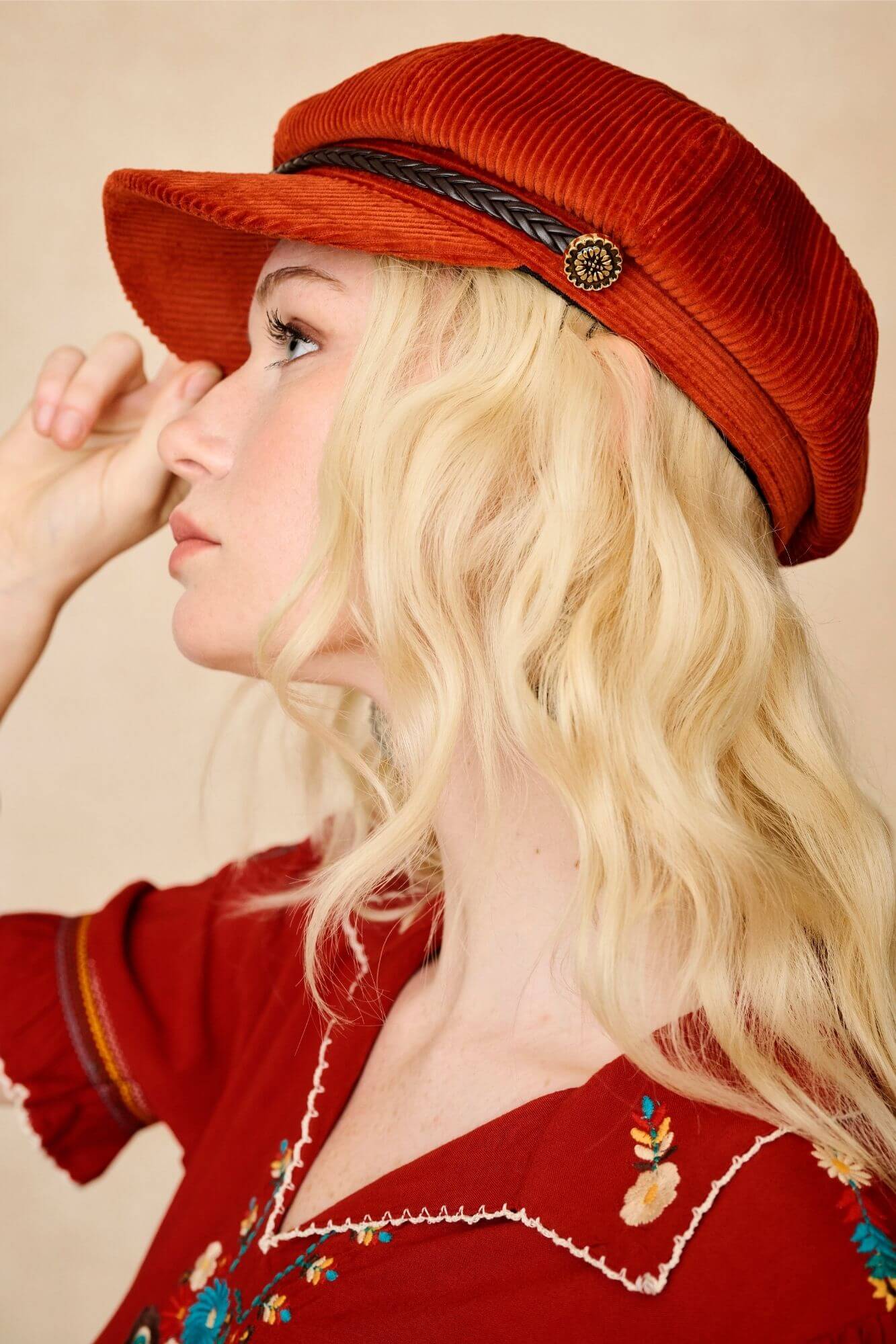Model wears burnt orange corduroy baker hat with braided trim and vintage detailing. A 70s-inspired boho hat by The Hippie Shake. Side view
