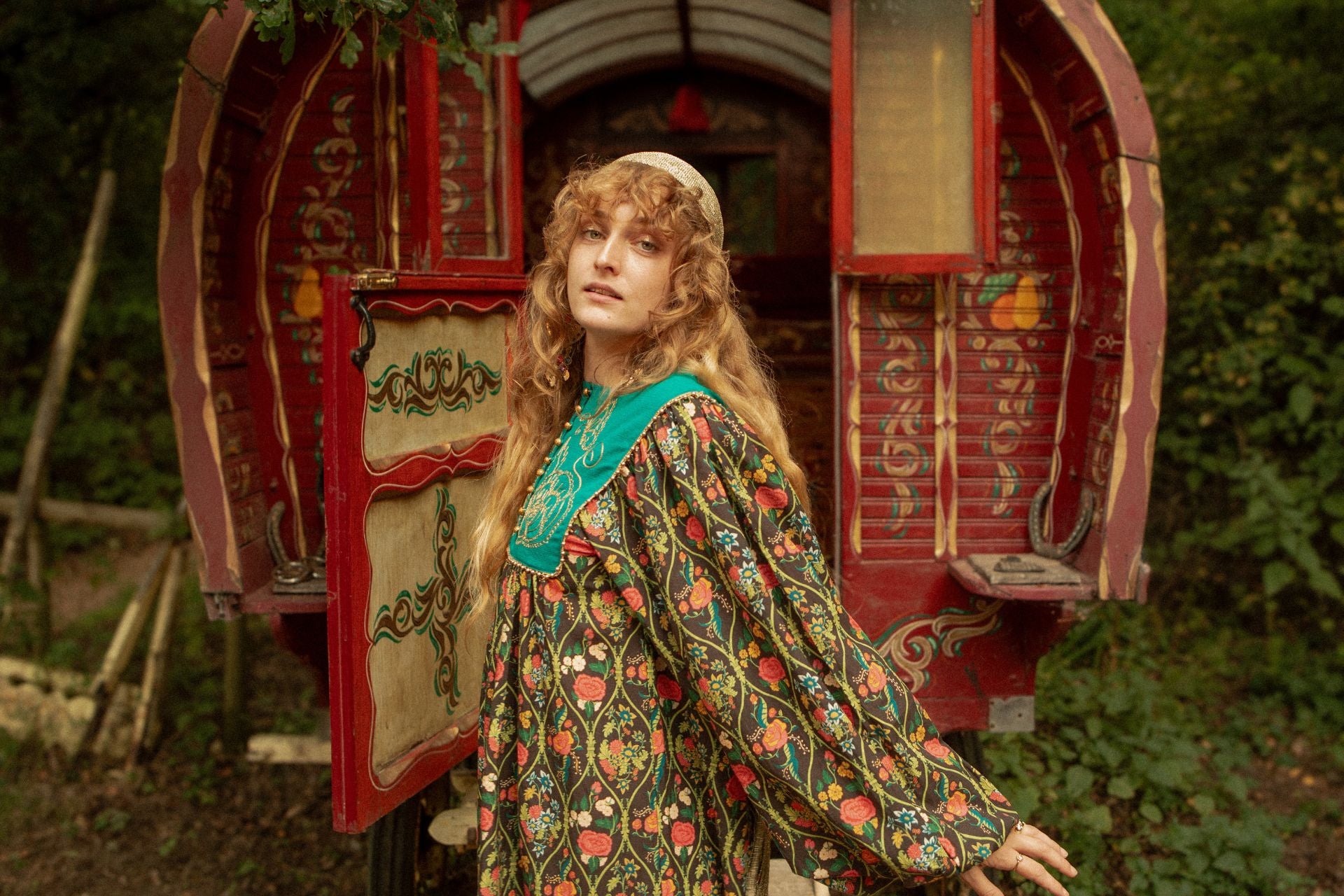 The Hippie Shake Tales of Time Collection hero image of a model in a floral dress in front of a red hand painted caravan