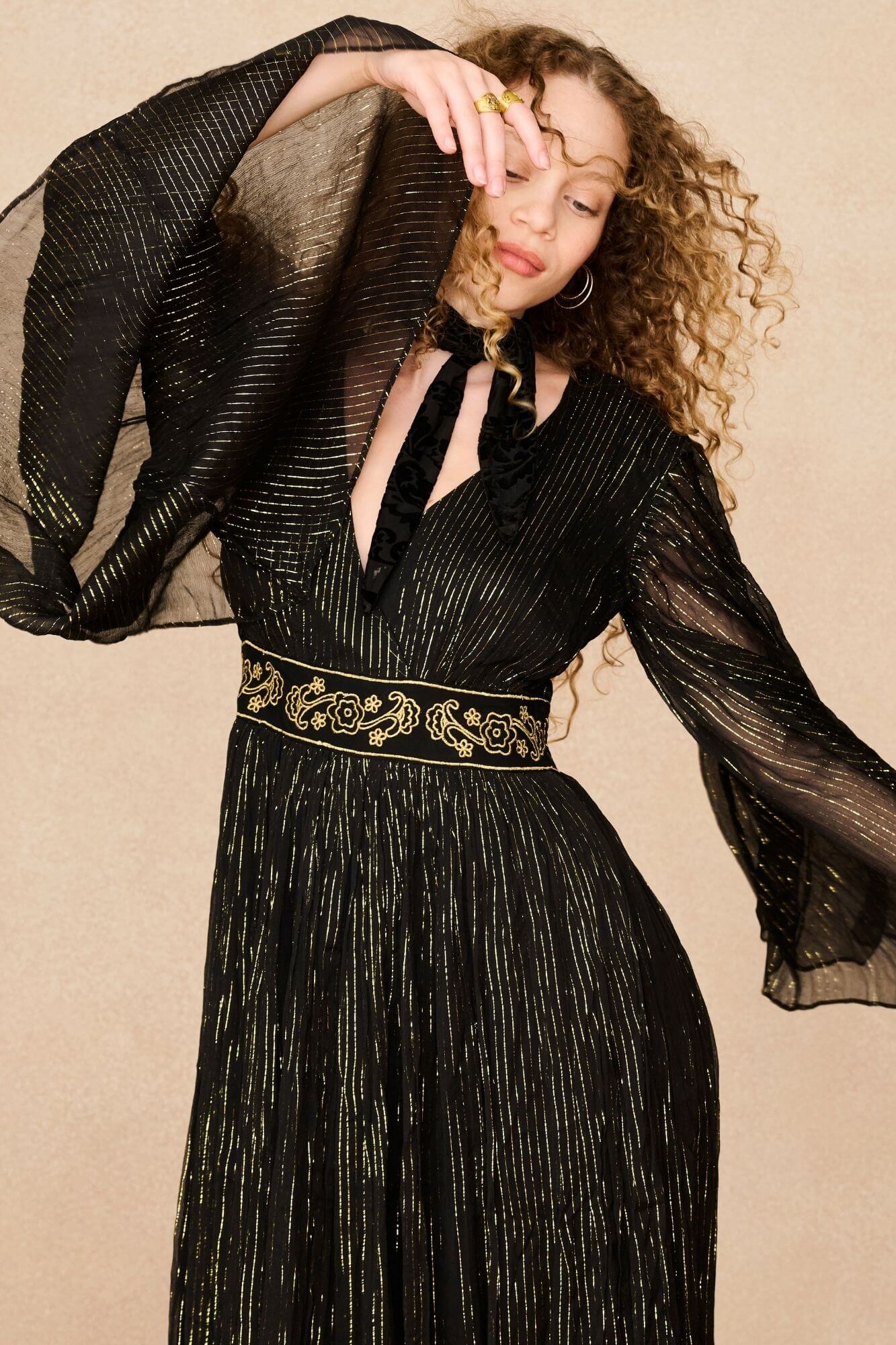 A model wearing a black maxi dress with sheer long flowy sleeves by the Hippie Shake