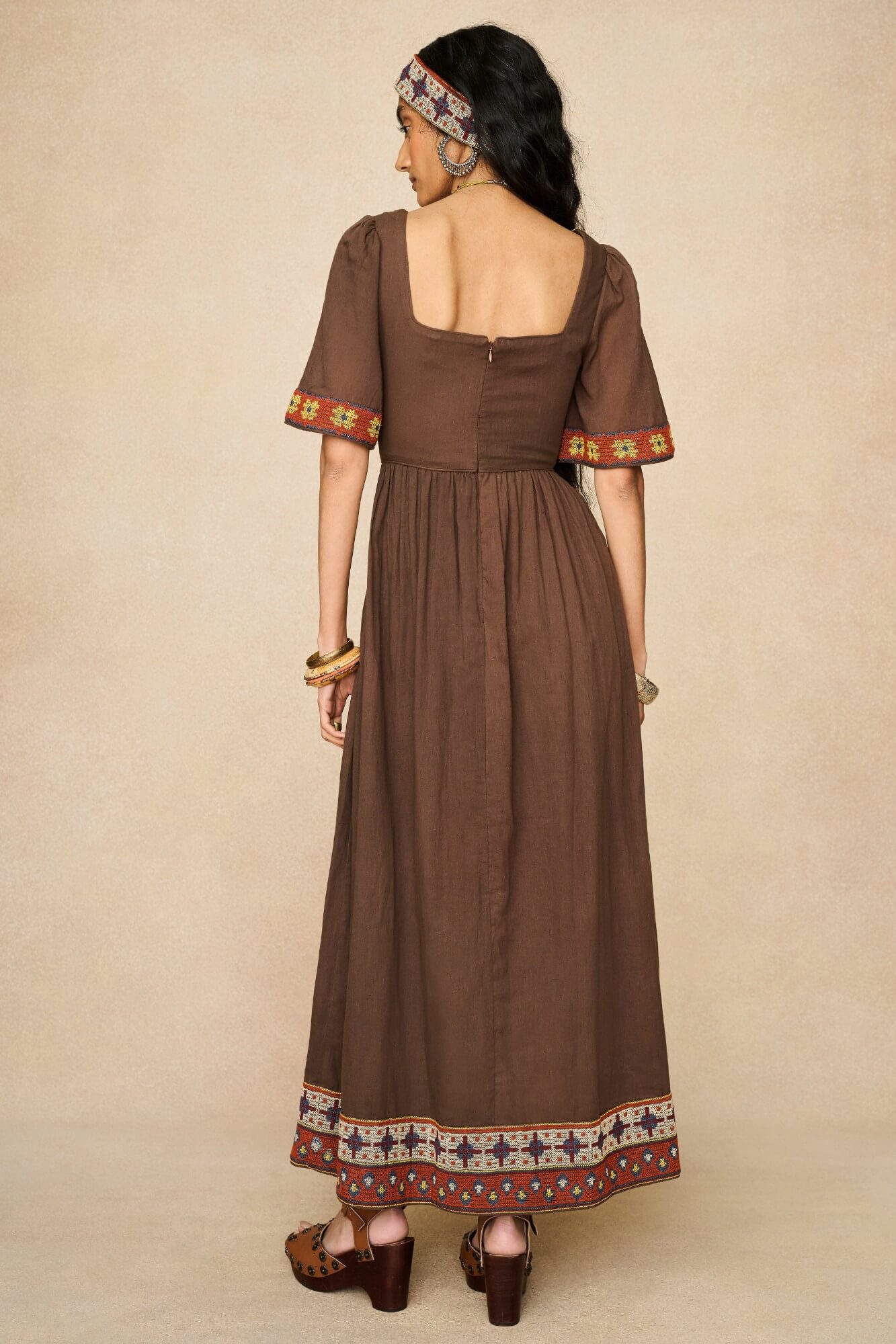 Model wearing brown embroidered maxi dress by The Hippie Shake, back view
