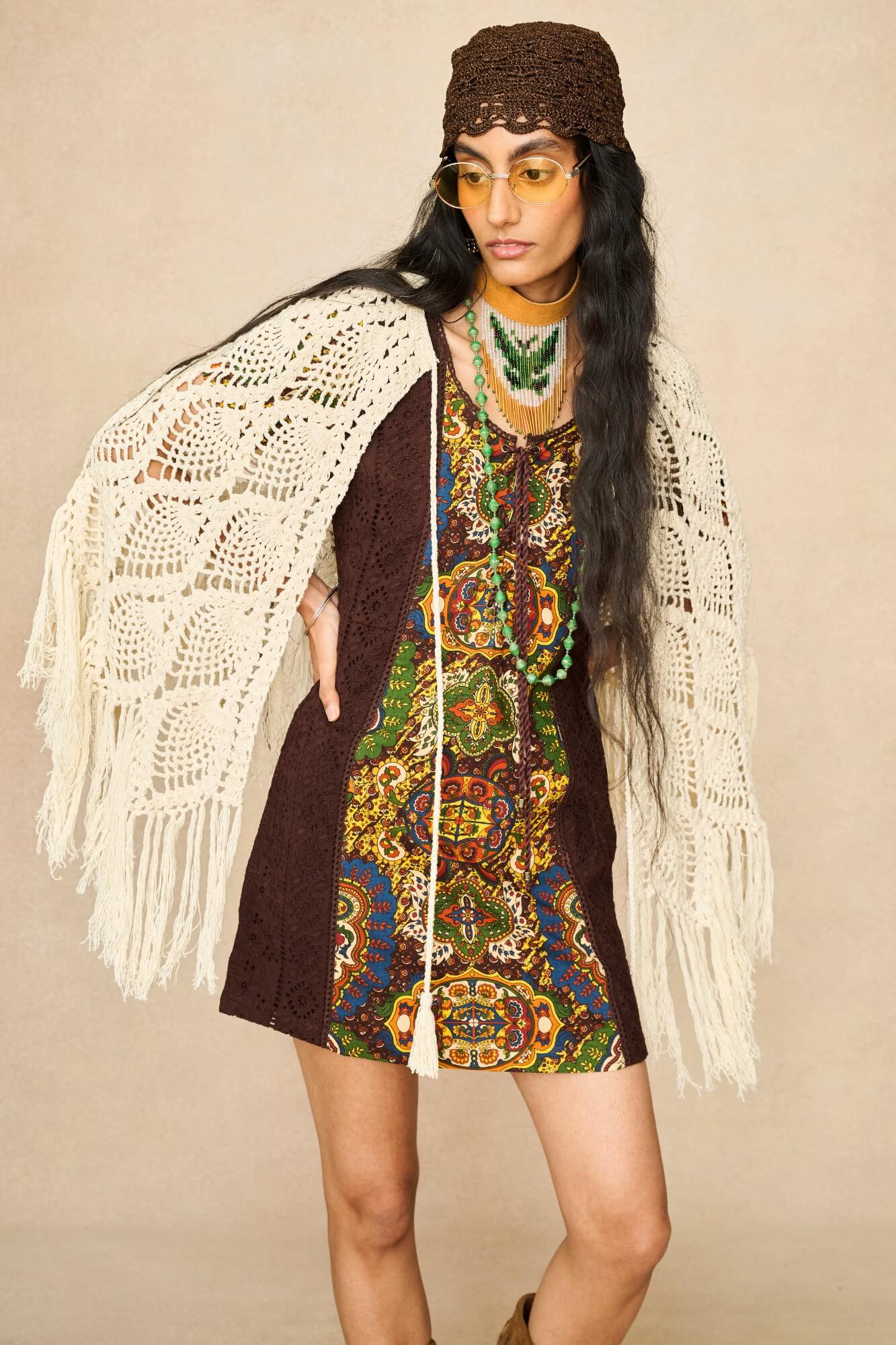 Model wearing cream crochet cape with 70s printed mini dress by The Hippie Shake, front view