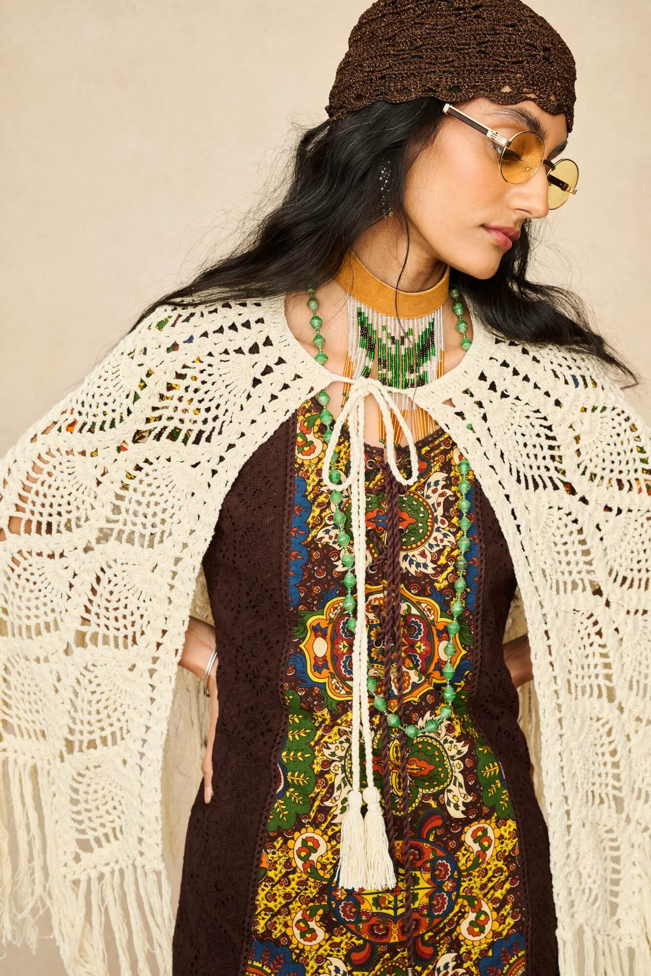 Model wearing cream crochet cape with 70s printed mini dress by The Hippie Shake, close up