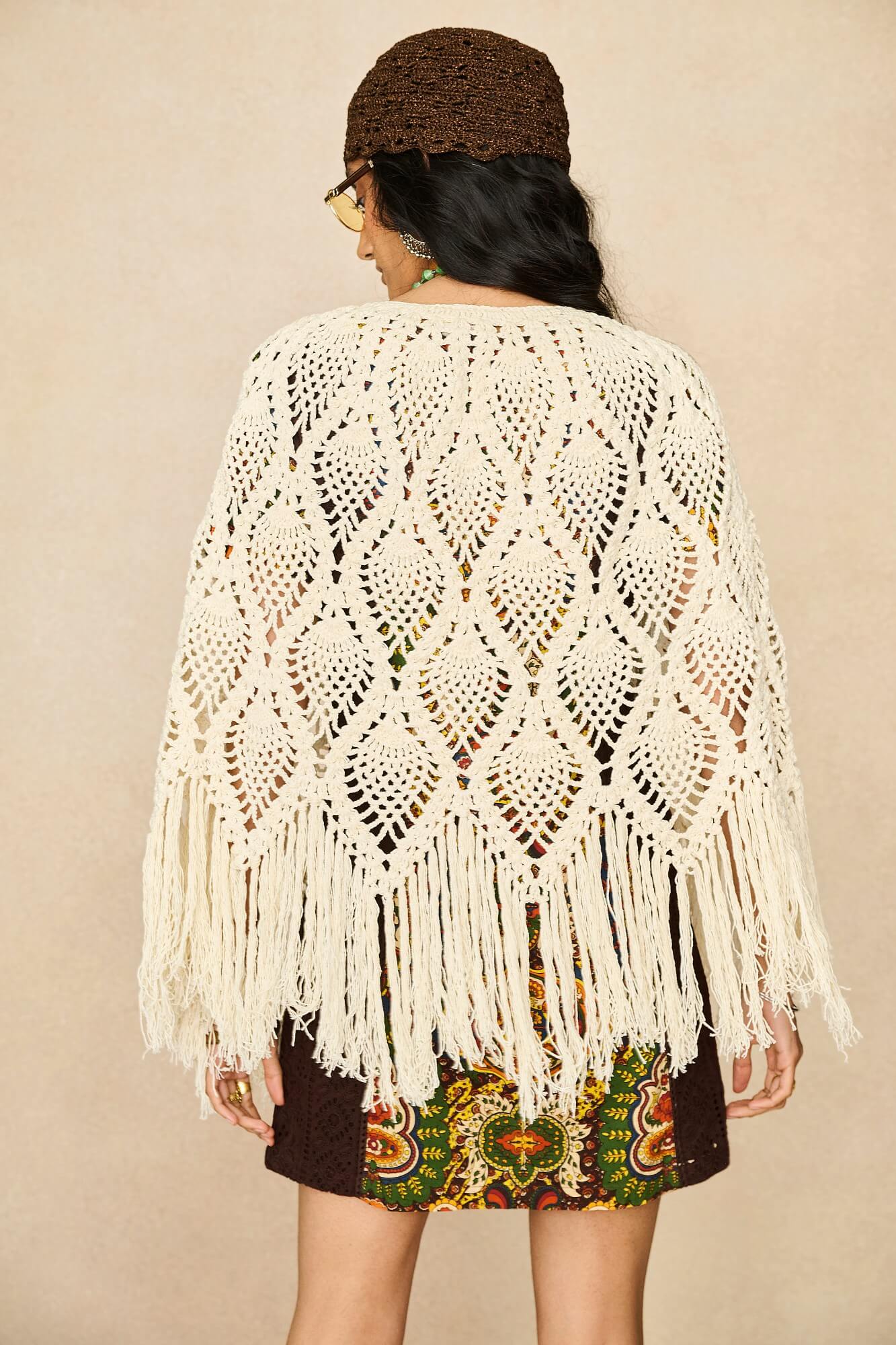 Model wearing cream crochet cape with 70s printed mini dress by The Hippie Shake, back view