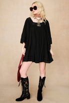 Model wearing 70s black mini dress with lace-up Penny Lane boots by The Hippie Shake, front view