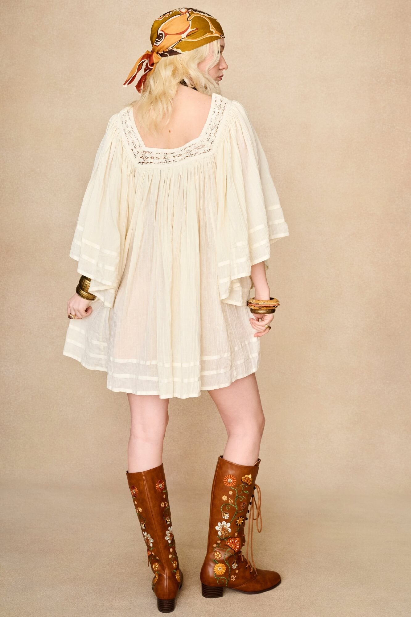 Model wearing 70s cream mini dress with lace-up Penny Lane boots by The Hippie Shake, back view