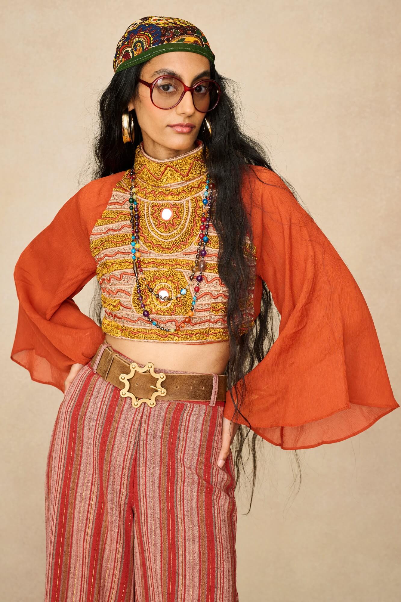 Model wearing 70s orange beaded top with striped trousers by The Hippie Shake, front view