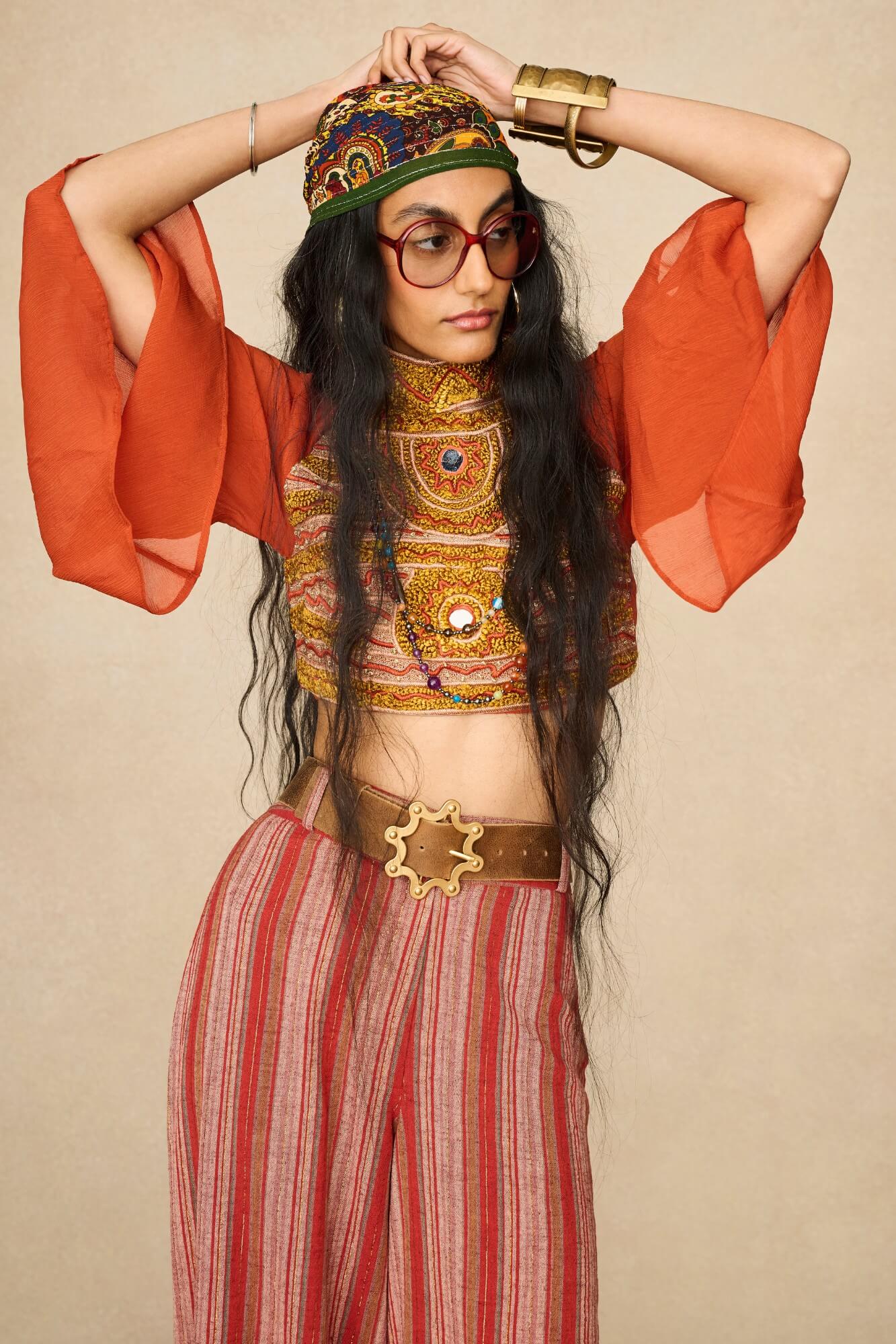 Model wearing 70s orange beaded top with striped trousers by The Hippie Shake, front view