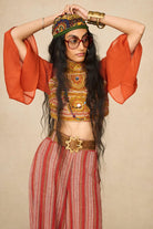 Model wearing 70s orange beaded top with striped trousers by The Hippie Shake, front view