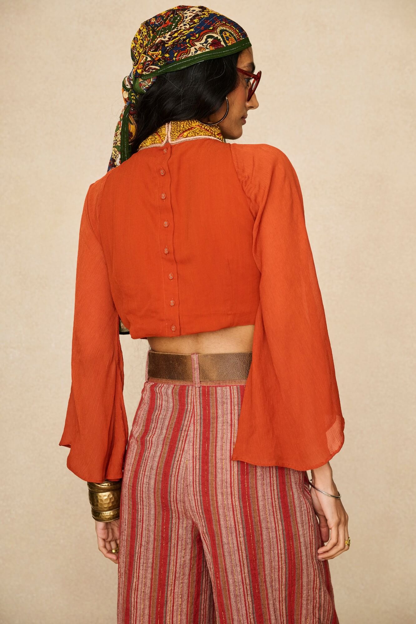 Model wearing 70s orange beaded top with striped trousers by The Hippie Shake, back view