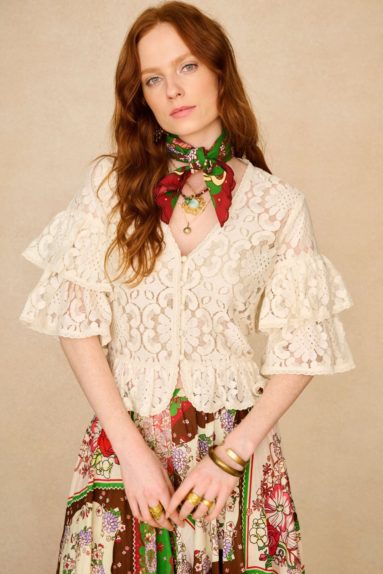 Woman wearing a lace top and colorful skirt with a neutral background