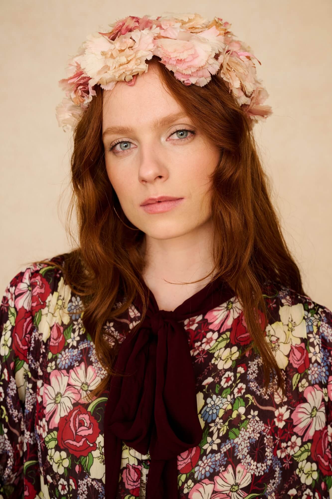 Woman wearing a floral headband and floral top against a beige background
