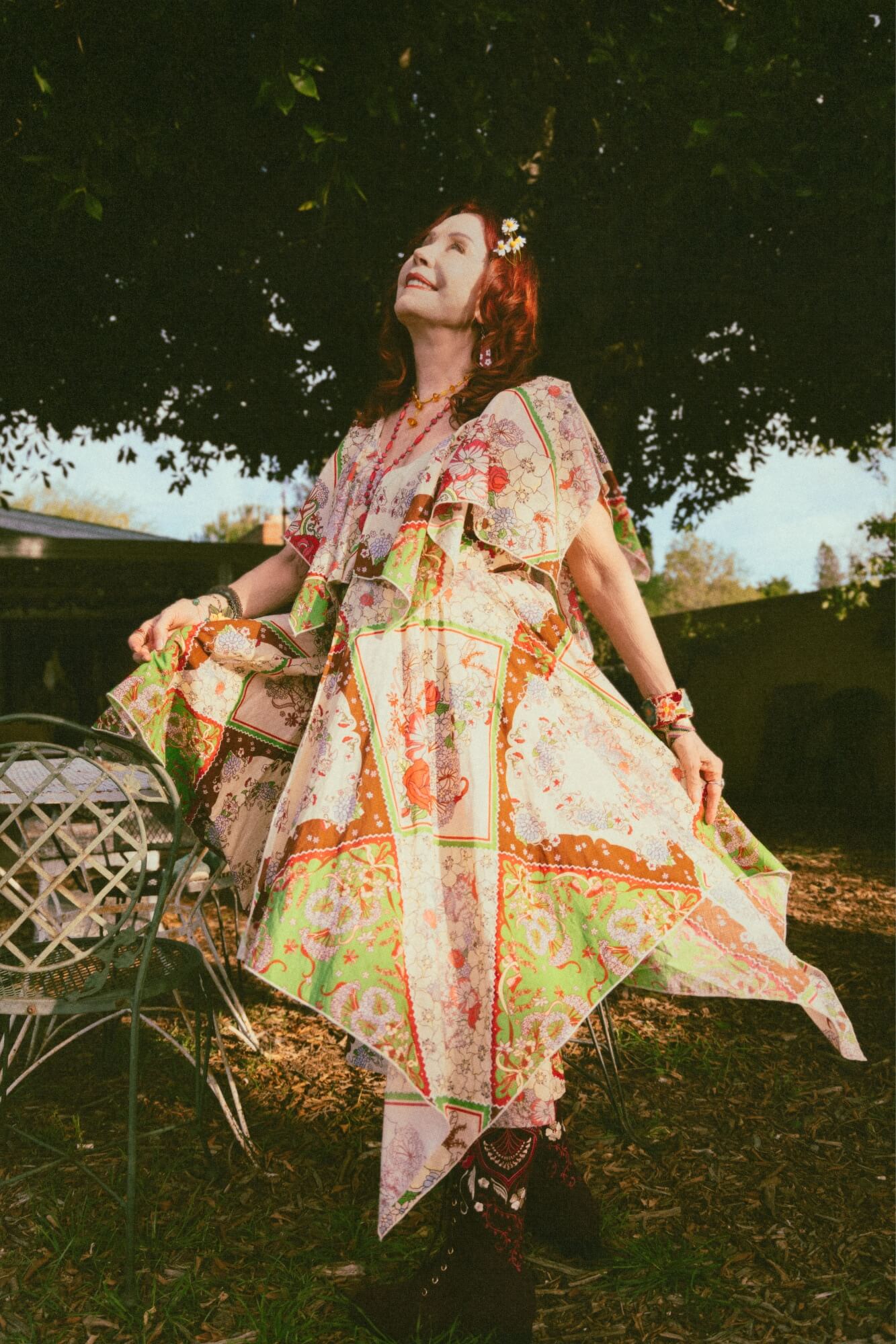 Woman in a patterned dress standing outdoors with trees in the background