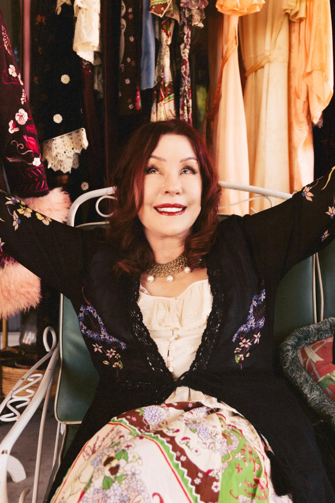 Person in a vintage closet with colorful garments and accessories.