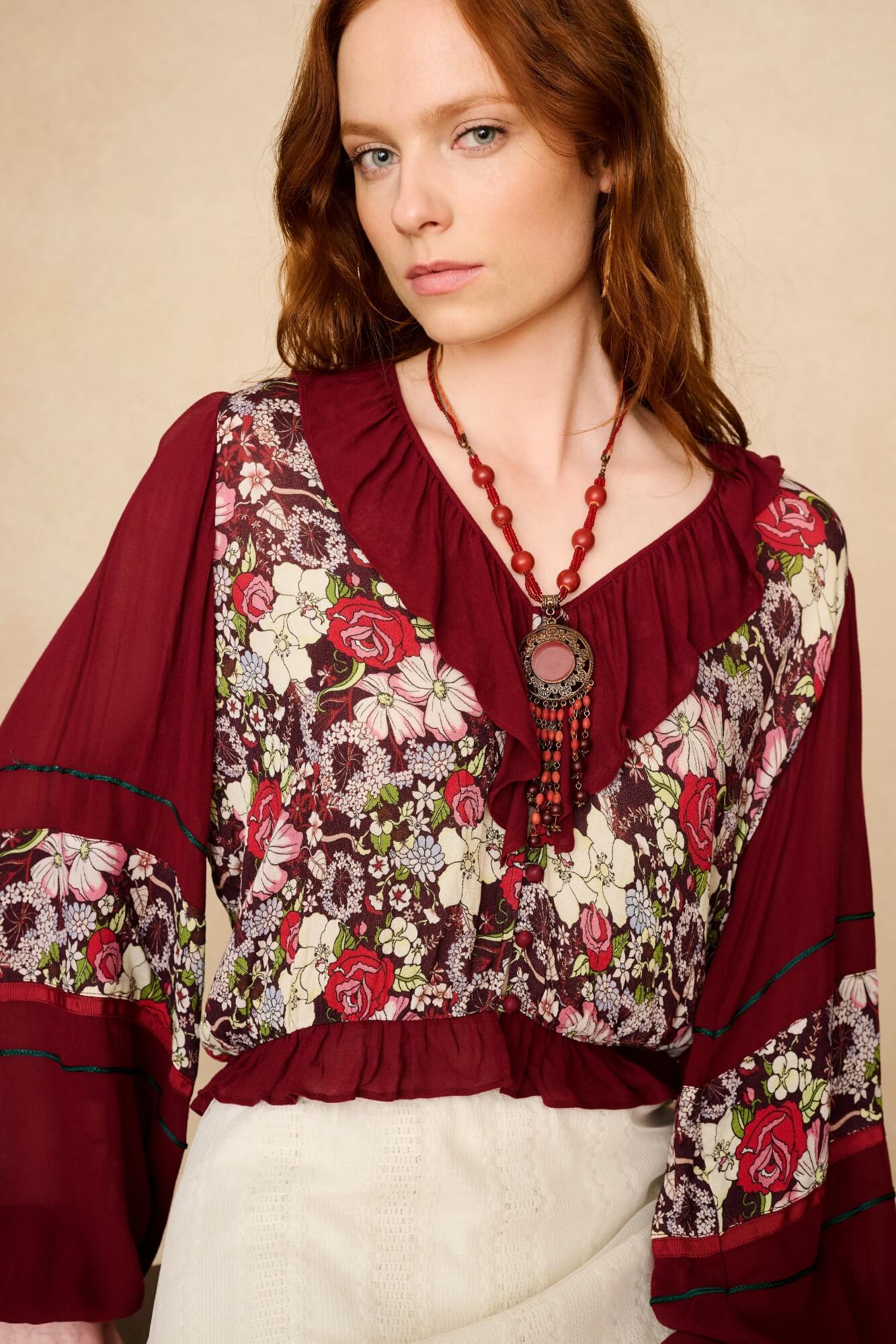 Woman wearing a floral blouse with burgundy accents on a beige background