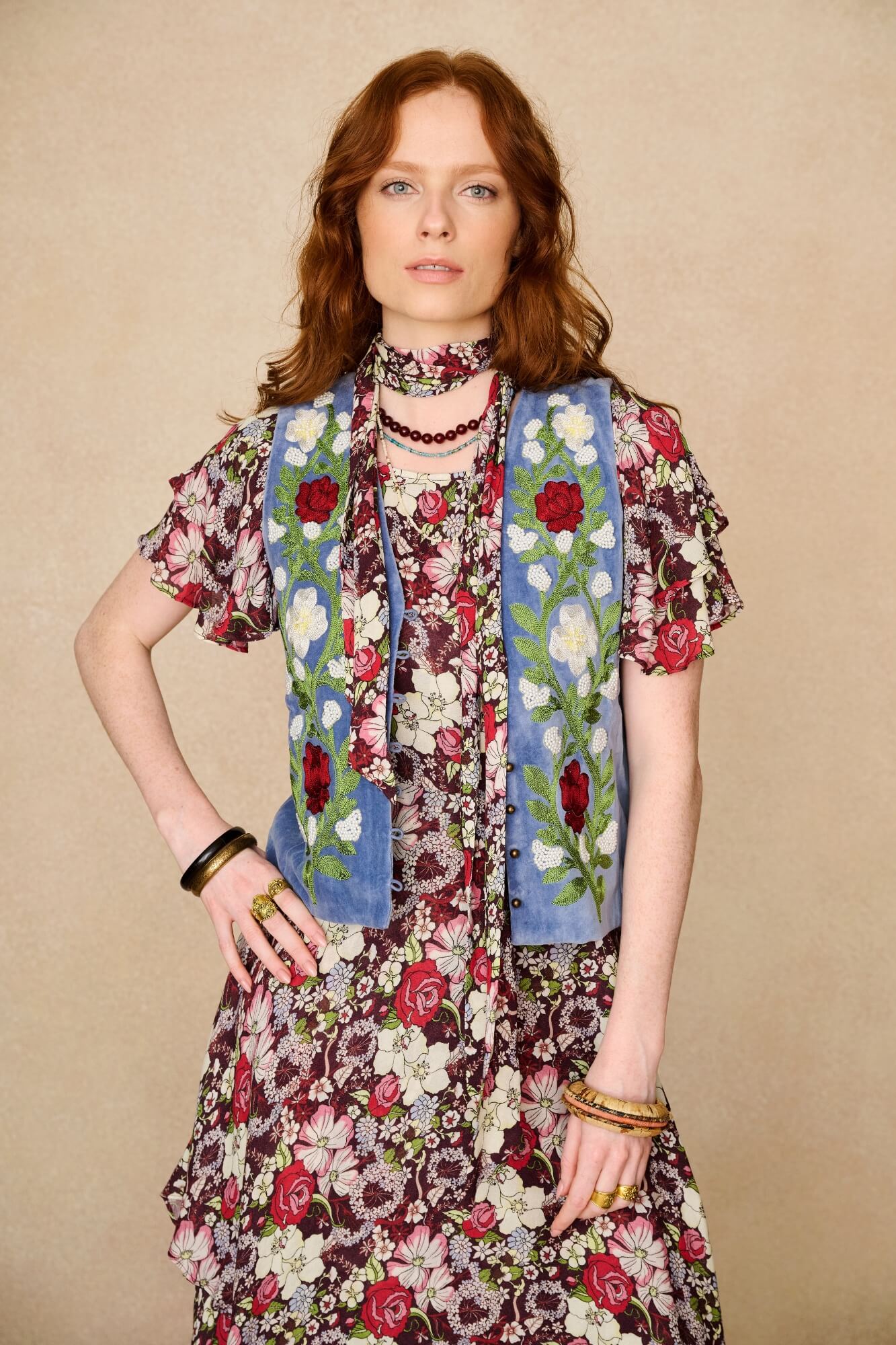 woman wears embroidered blue vest and floral dress - close up