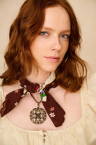 Woman wearing a decorative scarf with a large pendant on a beige background
