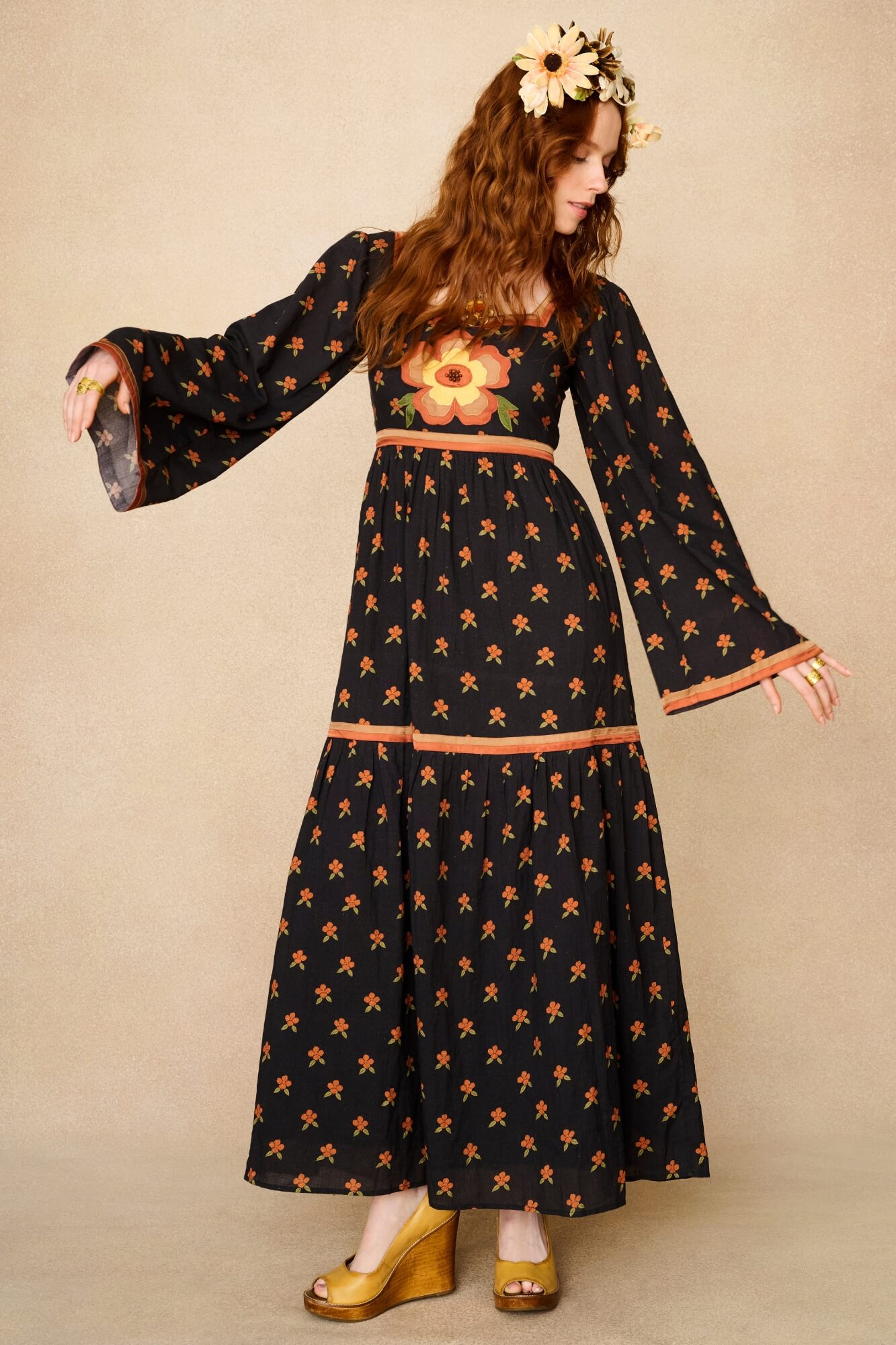 Woman wearing a black dress with orange floral patterns against a beige background