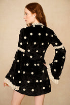 Black dress with white polka dots and lace details on a beige background