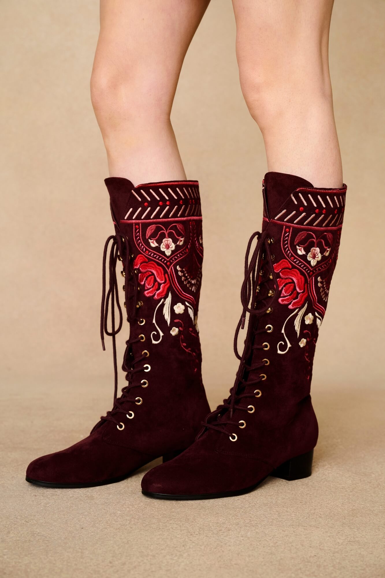 Burgundy embroidered boots on a beige background