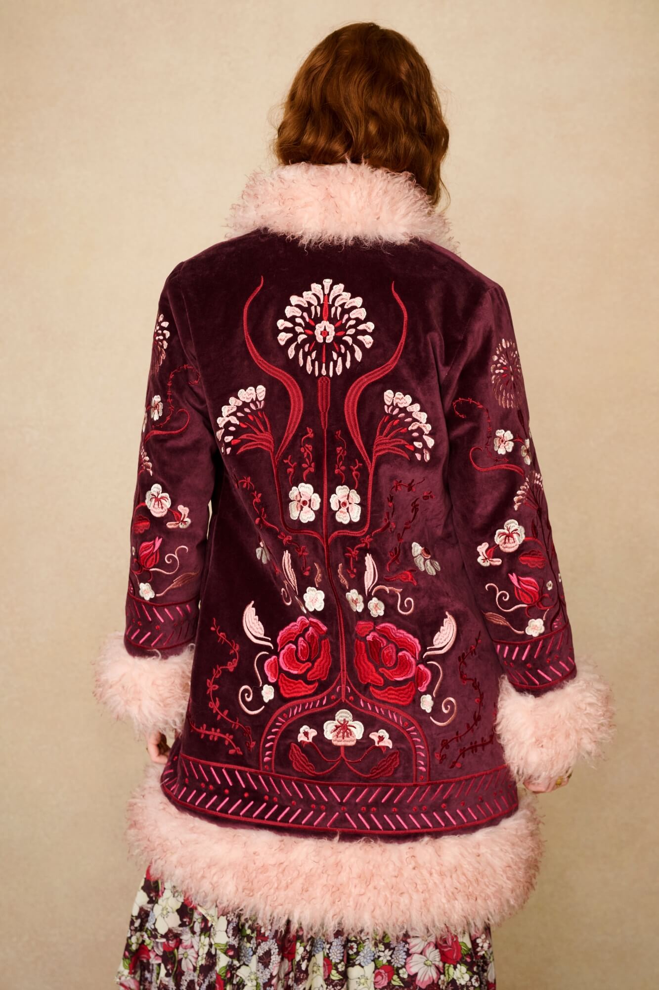 Embroidered jacket with floral patterns and pink fur trim on a beige background - back shot