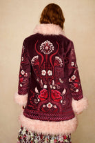 Embroidered jacket with floral patterns and pink fur trim on a beige background - back shot