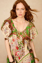 Woman wearing a colorful patterned dress against a beige background - close up