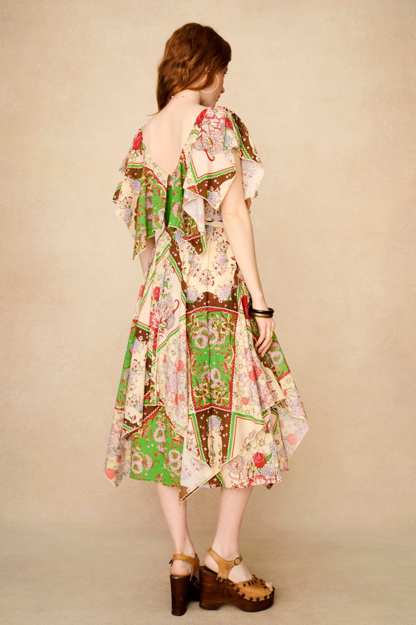 Woman wearing a colorful patterned dress against a beige background