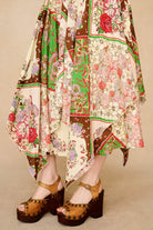 Person wearing a colorful patterned dress with wooden clogs on a beige background