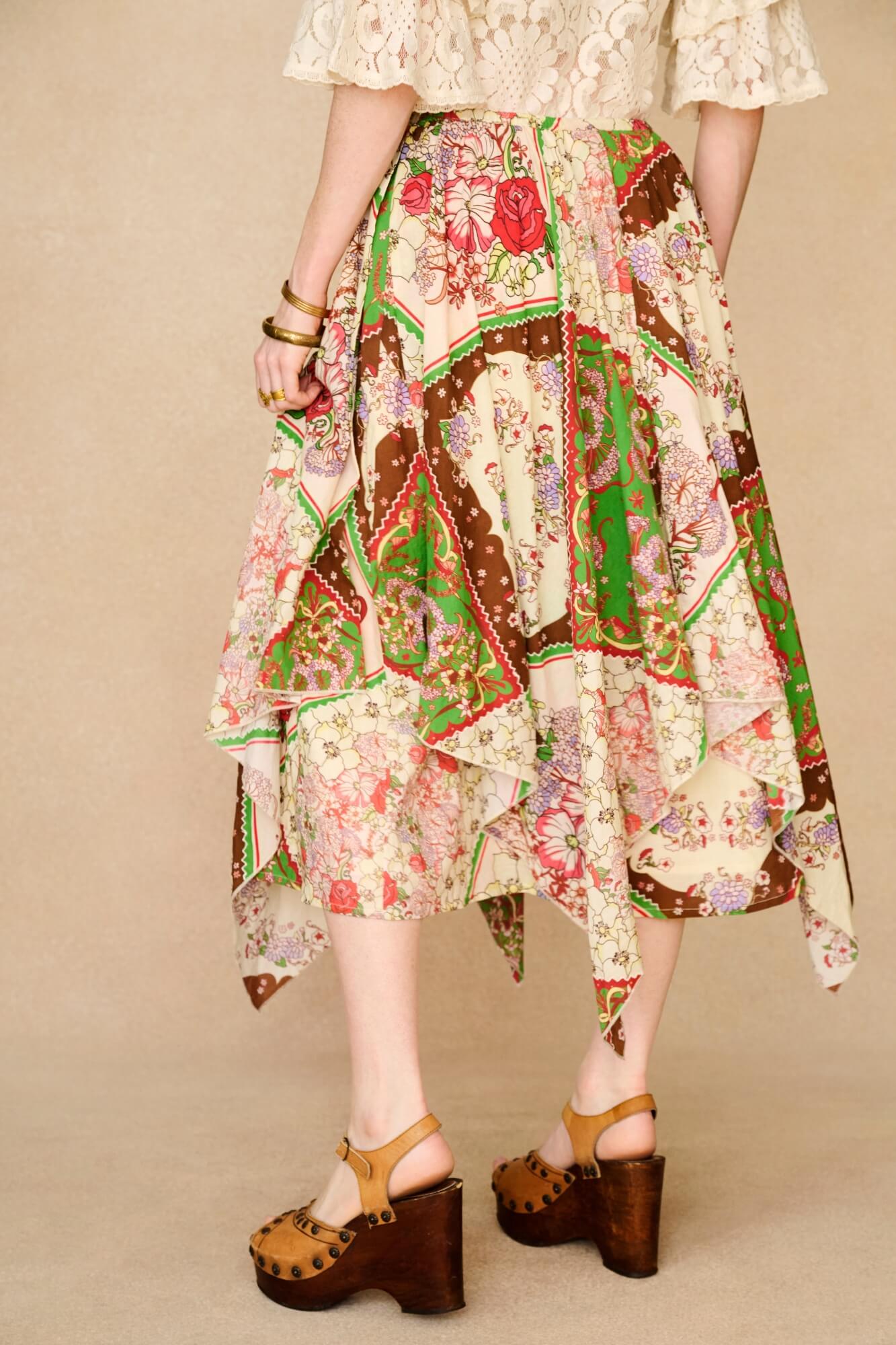 Person wearing a colorful patchwork skirt on a beige background