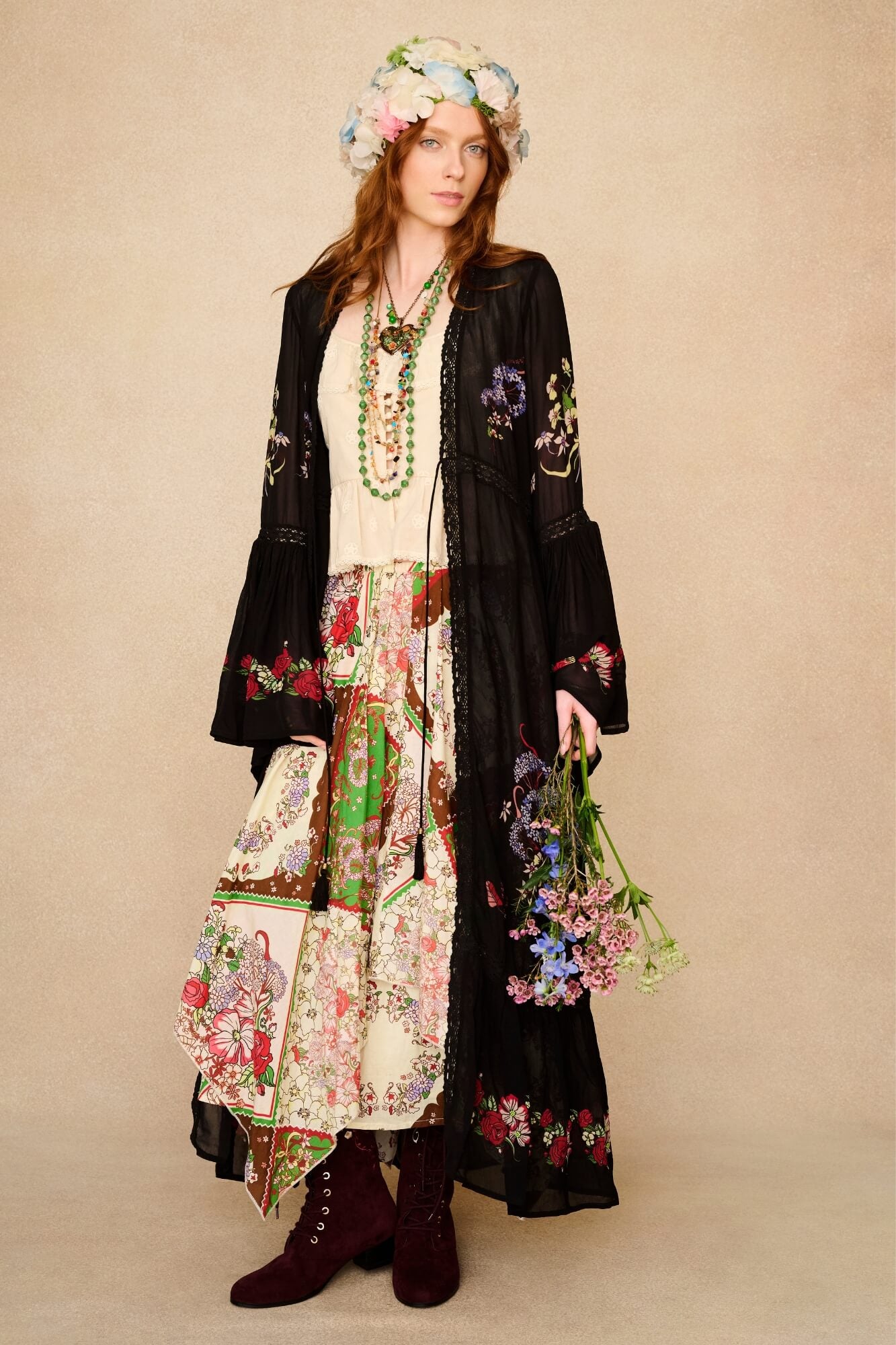 Woman wearing a floral dress and black duster with a beige background