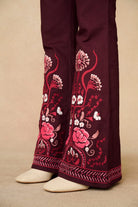 Burgundy  pants with pink floral embroidery on a beige background