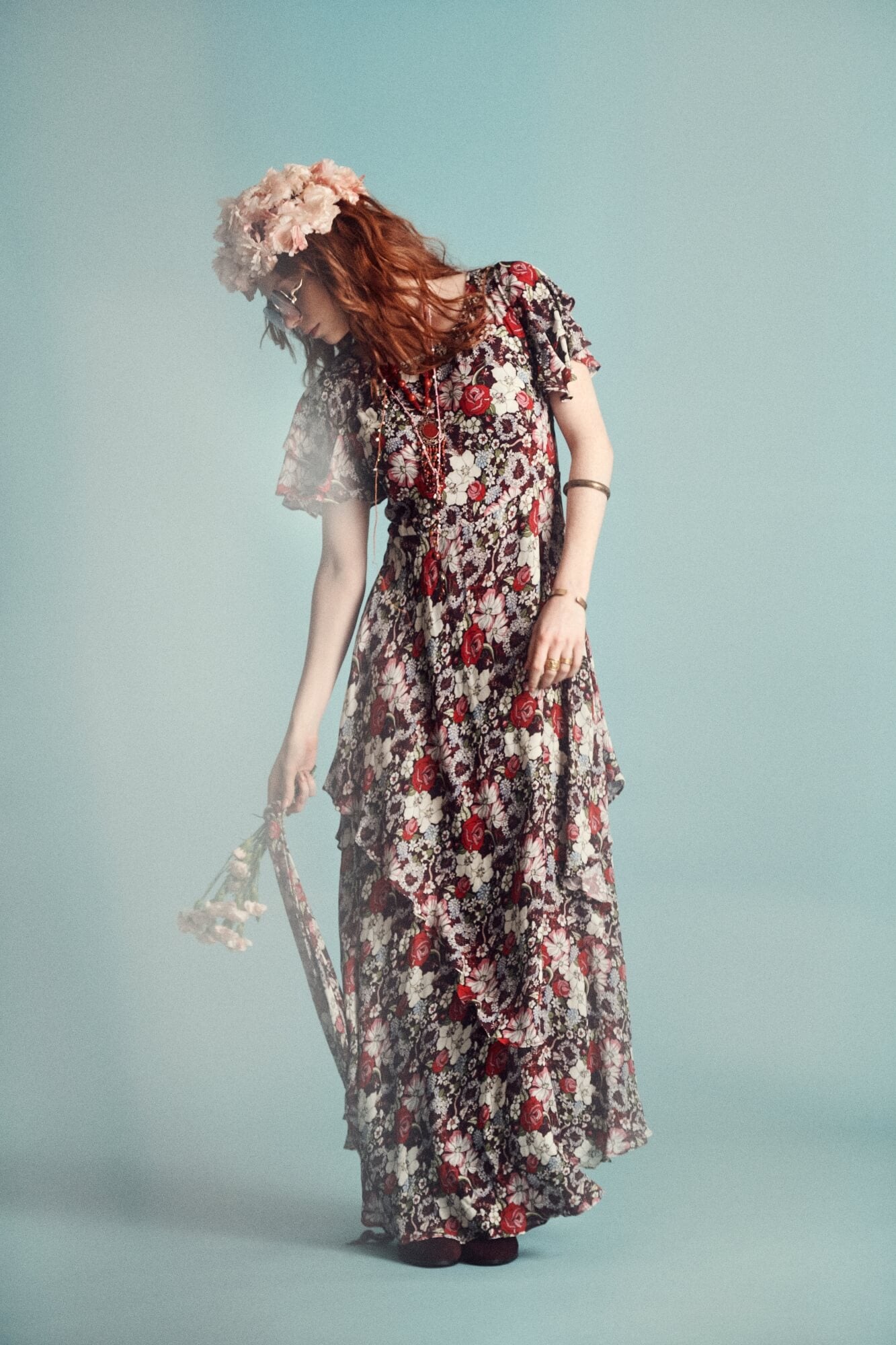 woman wears floral 70s dress with blue background behind
