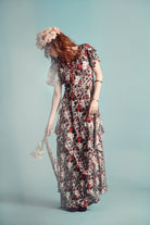 woman wears floral 70s dress with blue background behind